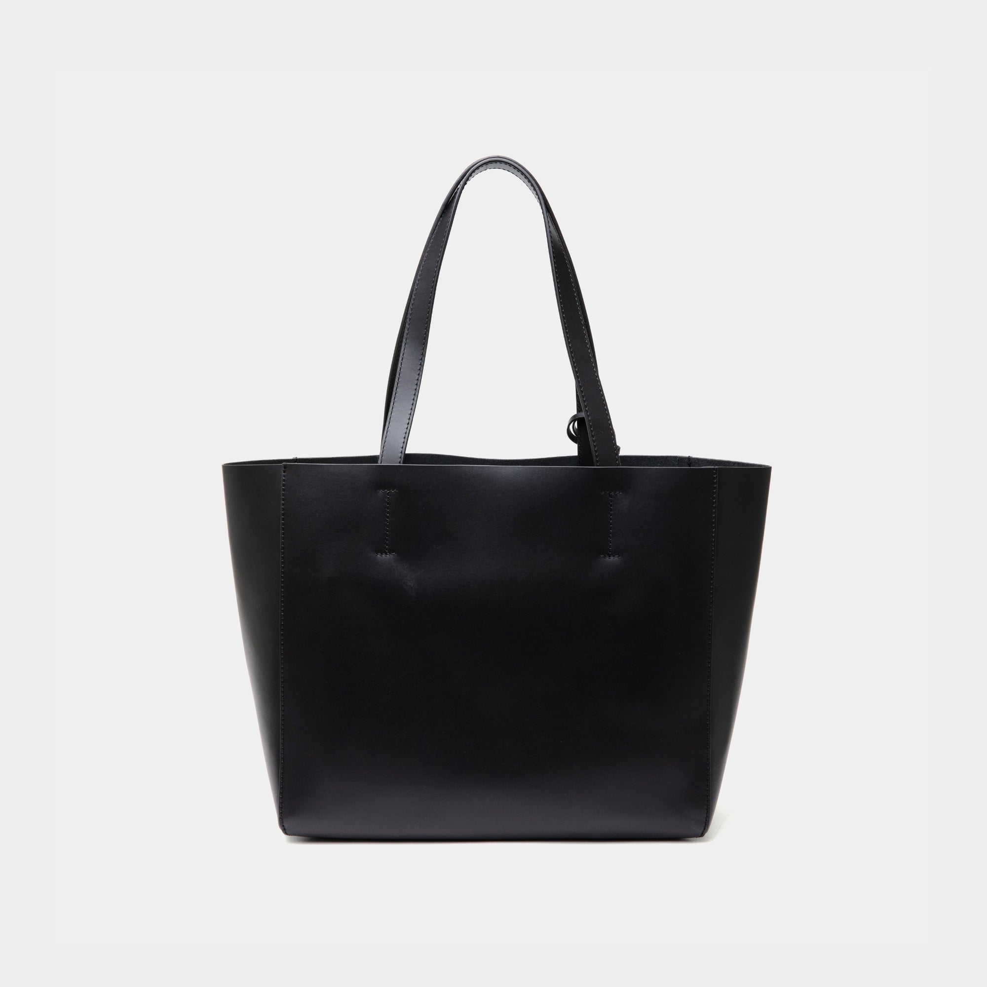 The back view of the black MOONSHAFT tote bag displayed against a white background. The bag features a sleek, minimalist design with reinforced stitching along the handles, emphasizing its spacious and structured silhouette.