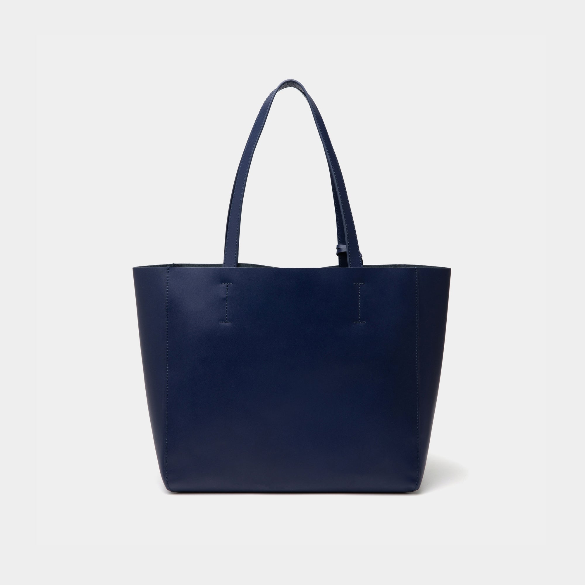 The back view of the navy MOONSHAFT tote bag displayed against a white background. The bag features a sleek, minimalist design with reinforced stitching along the handles, emphasizing its spacious and structured silhouette.