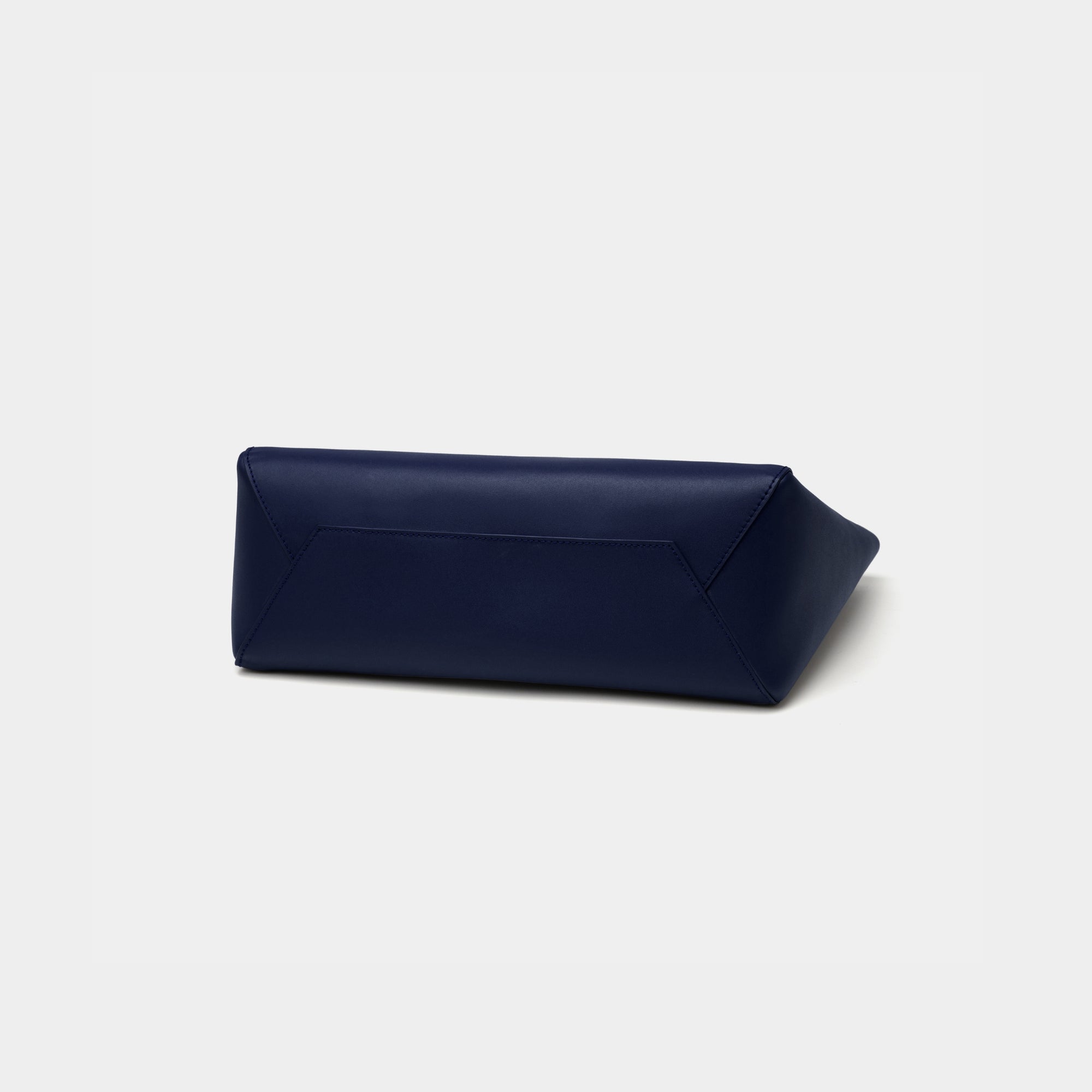 The bottom view of the navy MOONSHAFT tote bag displayed against a white background. The bag features a sleek, minimalist design with reinforced stitching along the handles, emphasizing its spacious and structured silhouette.