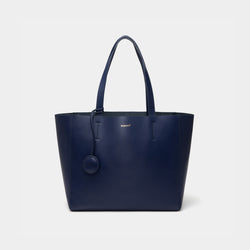 A minimalist navy leather tote bag displayed against a plain background. The tote features a smooth leather texture and a clean, structured design with no external embellishments, showcasing its simplicity and elegance. It has two sturdy leather handles and a spacious interior, making it a practical choice for everyday use. The neutral tan color adds to the bag’s versatile appeal, perfect for complementing various outfits and occasions.