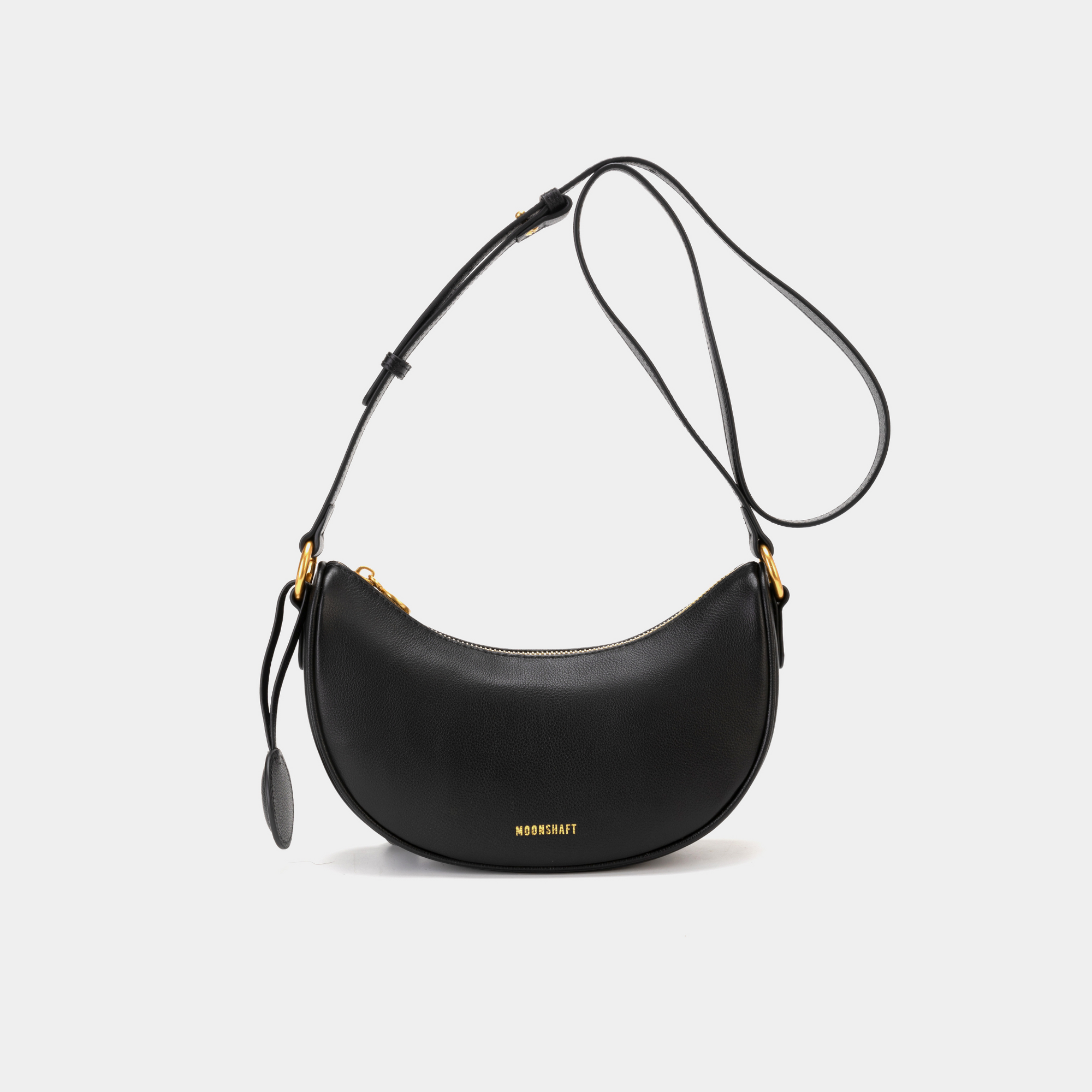 Front view of the Crescent Moon bag in black, featuring smooth leather with a minimalist design. The bag is shown with its adjustable crossbody strap and gold-tone hardware, highlighting the curved silhouette and simple elegance of the design.