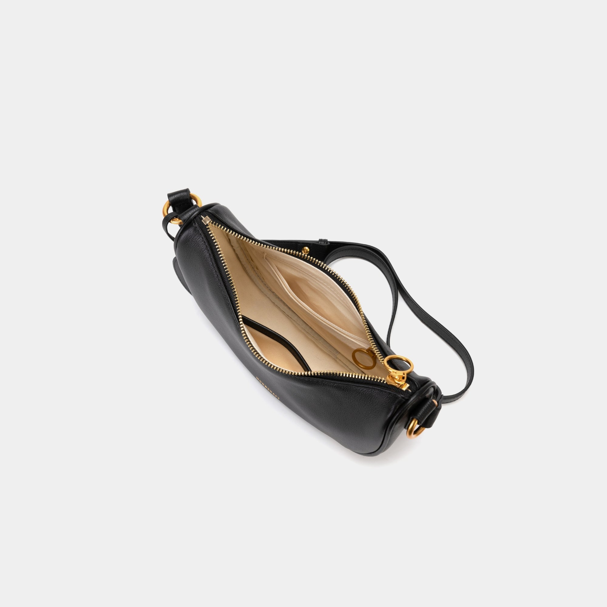 Top view of the Crescent Moon bag in black, showcasing the smooth leather exterior and gold zipper partially open, revealing the beige interior lining. The inside compartment features a simple yet spacious design with a small slip pocket for organization. The elegant contrast between the black leather and light interior is highlighted.