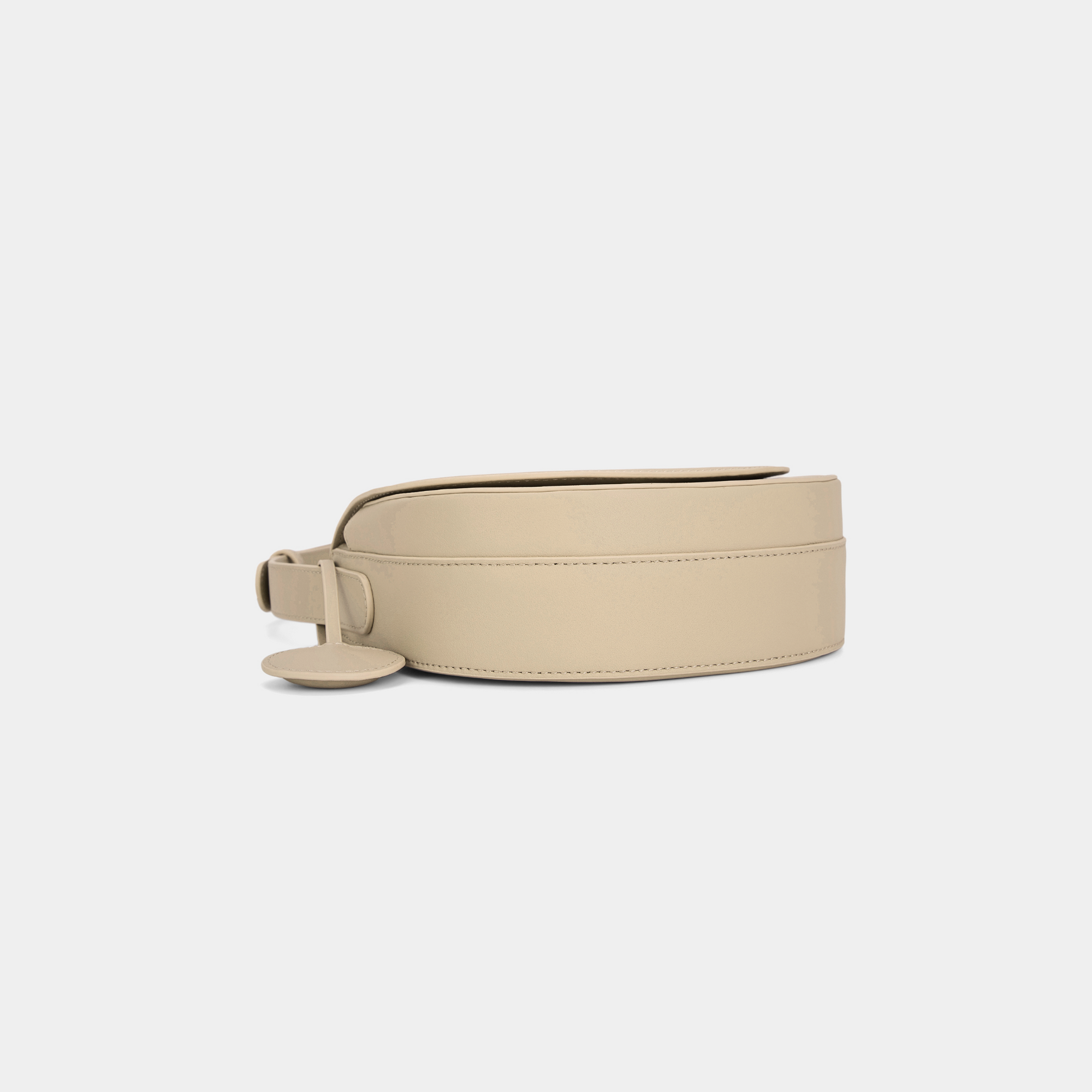 Bottom view of a beige half moon crossbody bag, highlighting the smooth leather texture and the circular leather tag detail.