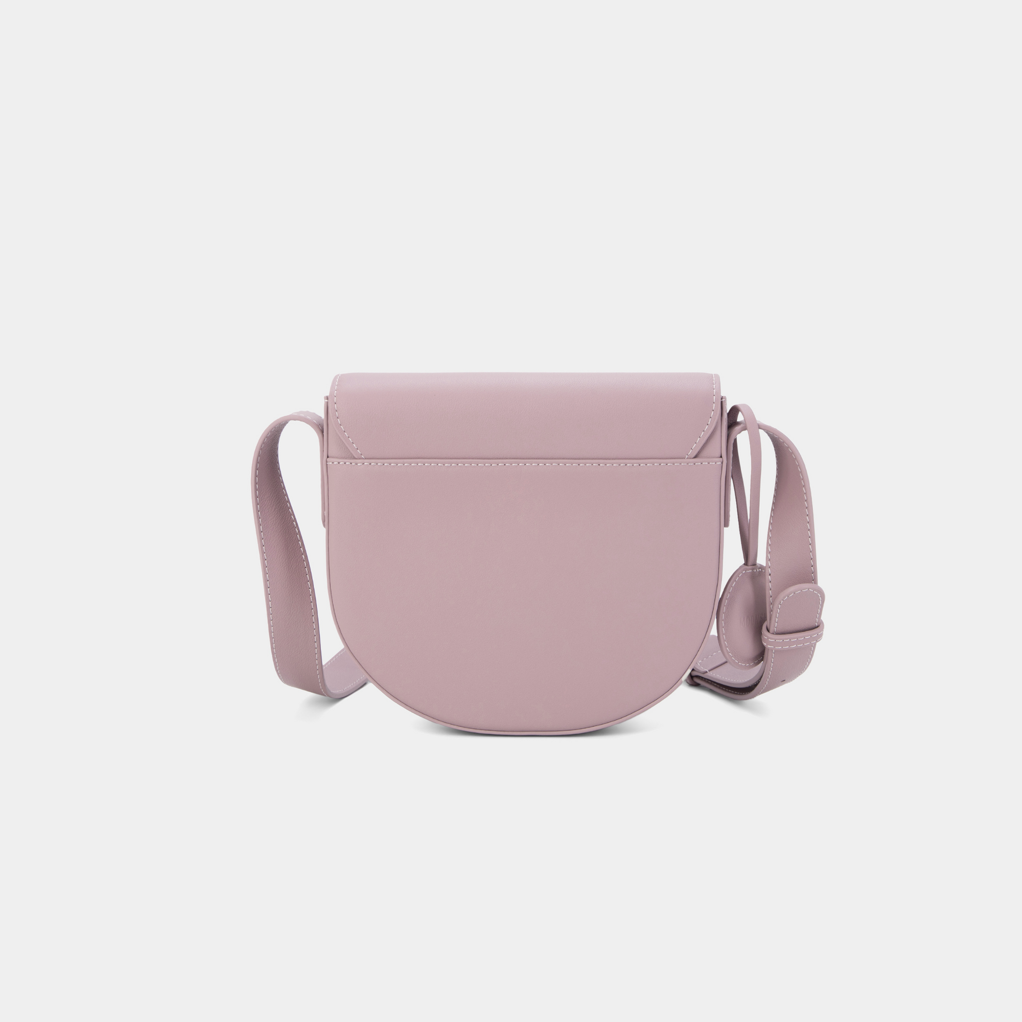 A back view of the half-moon crossbody bag in light lilac leather, showcasing its smooth, rounded structure. The back of the bag features clean, minimalist detailing, highlighting the high-quality craftsmanship. The adjustable strap connects seamlessly to the body of the bag, maintaining its sleek, functional design.