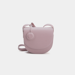 A Light Lilac half-moon crossbody bag with a sleek, smooth leather finish. It features a circular leather tag attached to the strap and a simple, structured design. The bag has a curved flap closure and an adjustable crossbody strap.