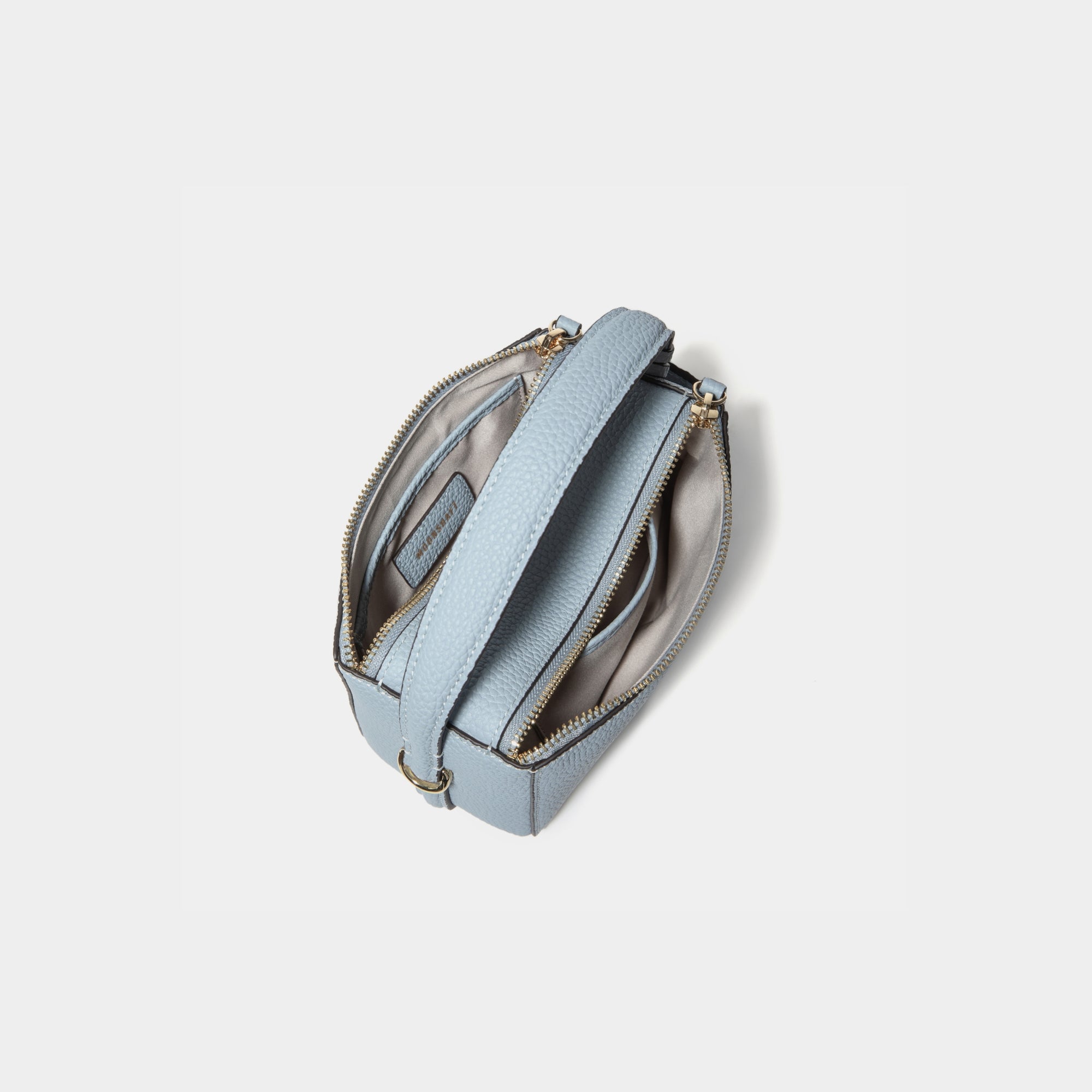 A top view of the Mini Double Zip Bag in aquamarine color, displaying its two spacious zippered compartments. The bag, made from pebbled leather, features a light-colored fabric lining for organized storage. The sturdy top handle and gold-tone hardware are visible, enhancing the bag’s functional and elegant design.