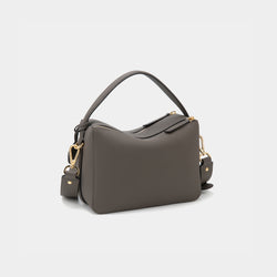 A back view of the upgraded double zip leather bag in charcoal, displayed at a diagonal angle. The pebbled leather texture and structured design are highlighted, with two parallel gold-tone zippers running across the back. The minimalist design and clean lines emphasize the bag’s high-quality craftsmanship.