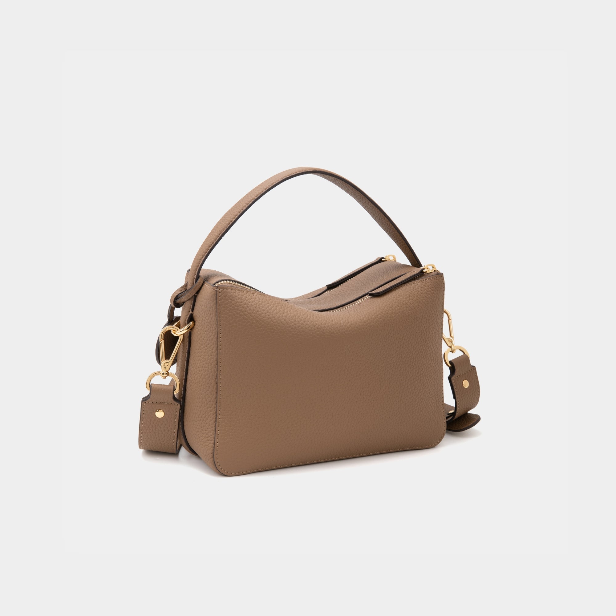A back view of the upgraded double zip leather bag in driftwood, displayed at a diagonal angle. The smooth leather texture and structured design are highlighted, with two parallel gold-tone zippers running across the back. The minimalist design and clean lines emphasize the bag’s high-quality craftsmanship.