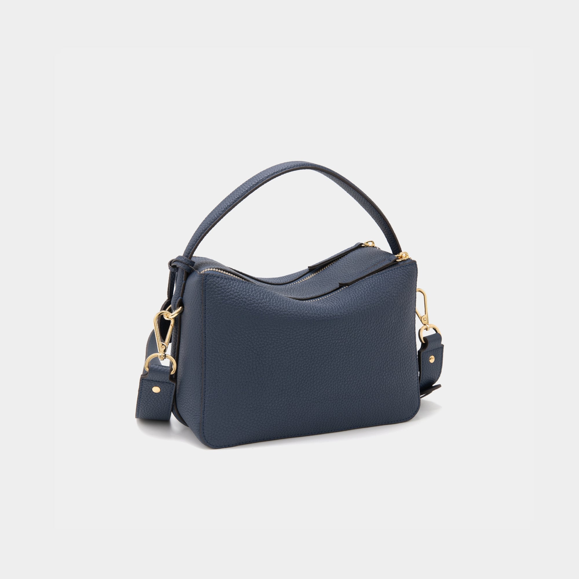 A back view of the upgraded double zip leather bag in marine blue, displayed at a diagonal angle. The pebbled leather texture and structured design are highlighted, with two parallel gold-tone zippers running across the back. The minimalist design and clean lines emphasize the bag’s high-quality craftsmanship.
