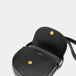 The close-up view displays the interior of the half-moon crossbody bag with its smooth leather flap open. A gold-tone magnetic closure is prominently featured, offering a secure and stylish fastening. The inner lining is minimalistic, with the brand name "MOONSHAFT" subtly embossed in gold just beneath the closure for a refined touch.
