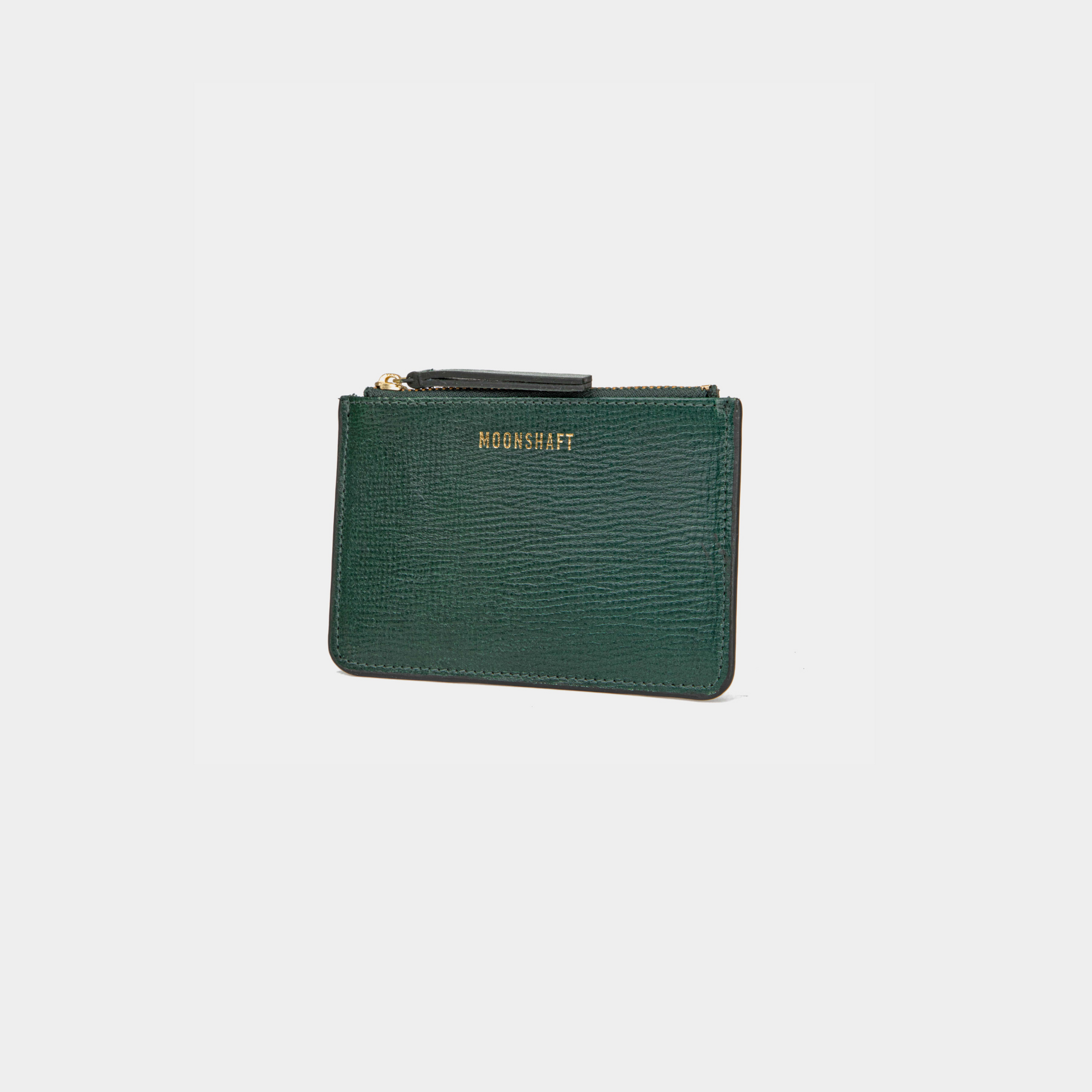 A dark green leather cardholder in a standing position, angled slightly to the right. The cardholder has a textured leather surface, with the MOONSHAFT logo embossed in gold at the top. The zipper closure at the top has gold-tone hardware, and there is a small leather zipper pull for ease of use.