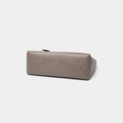 The bottom view of the taupe MOONSHAFT tote bag displayed against a white background. The bag features a sleek, minimalist design with reinforced stitching along the handles, emphasizing its spacious and structured silhouette.