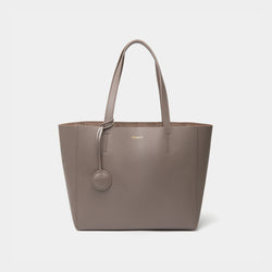 A minimalist taupe leather tote bag displayed against a plain background. The tote features a smooth leather texture and a clean, structured design with no external embellishments, showcasing its simplicity and elegance. It has two sturdy leather handles and a spacious interior, making it a practical choice for everyday use. The neutral tan color adds to the bag’s versatile appeal, perfect for complementing various outfits and occasions.