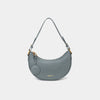 Front view of the Crescent Moon bag in ash blue, showcasing its smooth leather finish, curved silhouette, and gold hardware. The top handle is visible, along with an attached round coin purse accessory on the side. The minimal and elegant design highlights the bag's clean lines and structured shape.