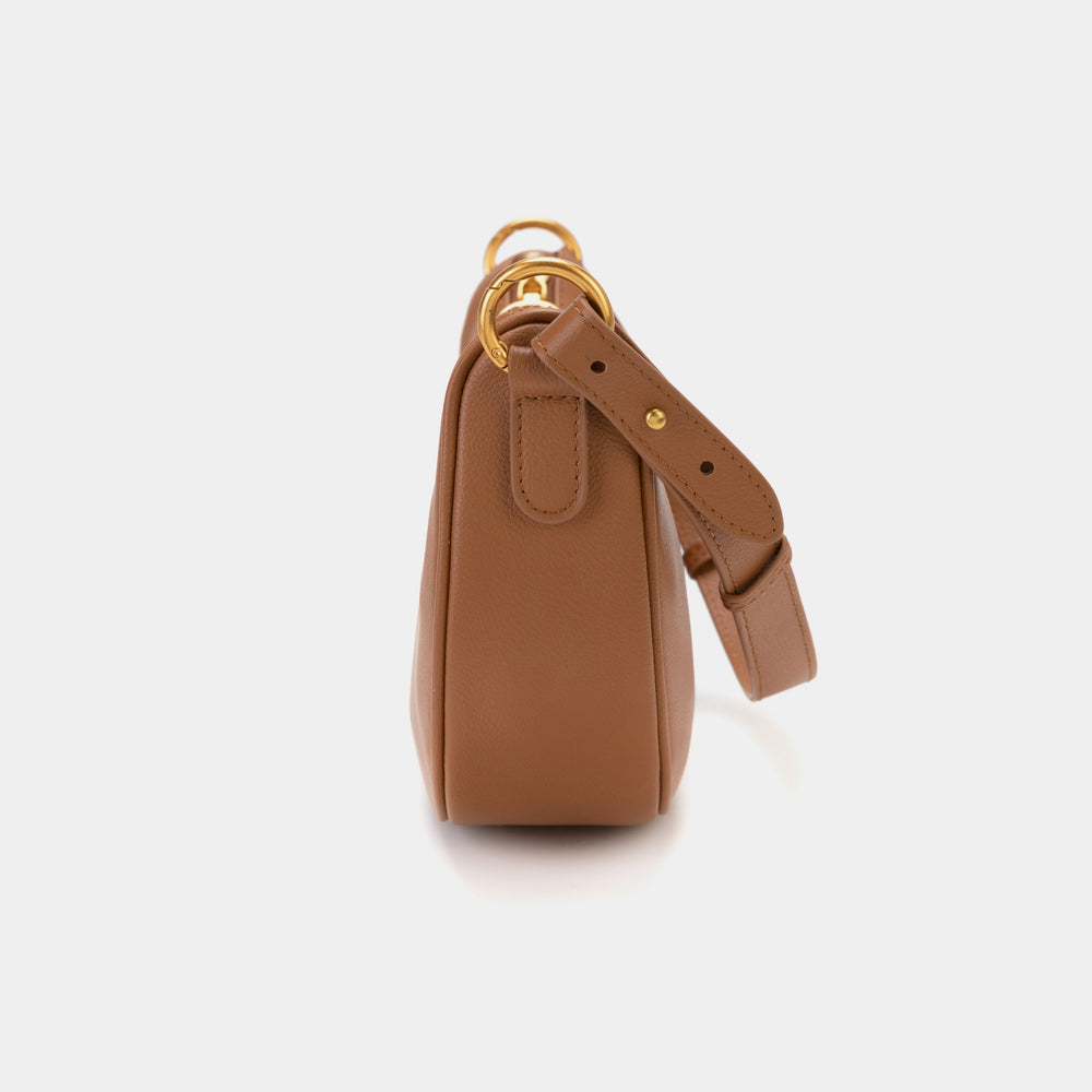 Side profile of the Crescent Moon bag in caramel color, highlighting the smooth leather, gold hardware, and minimalistic design. The image emphasizes the bag's structured body and sleek silhouette.