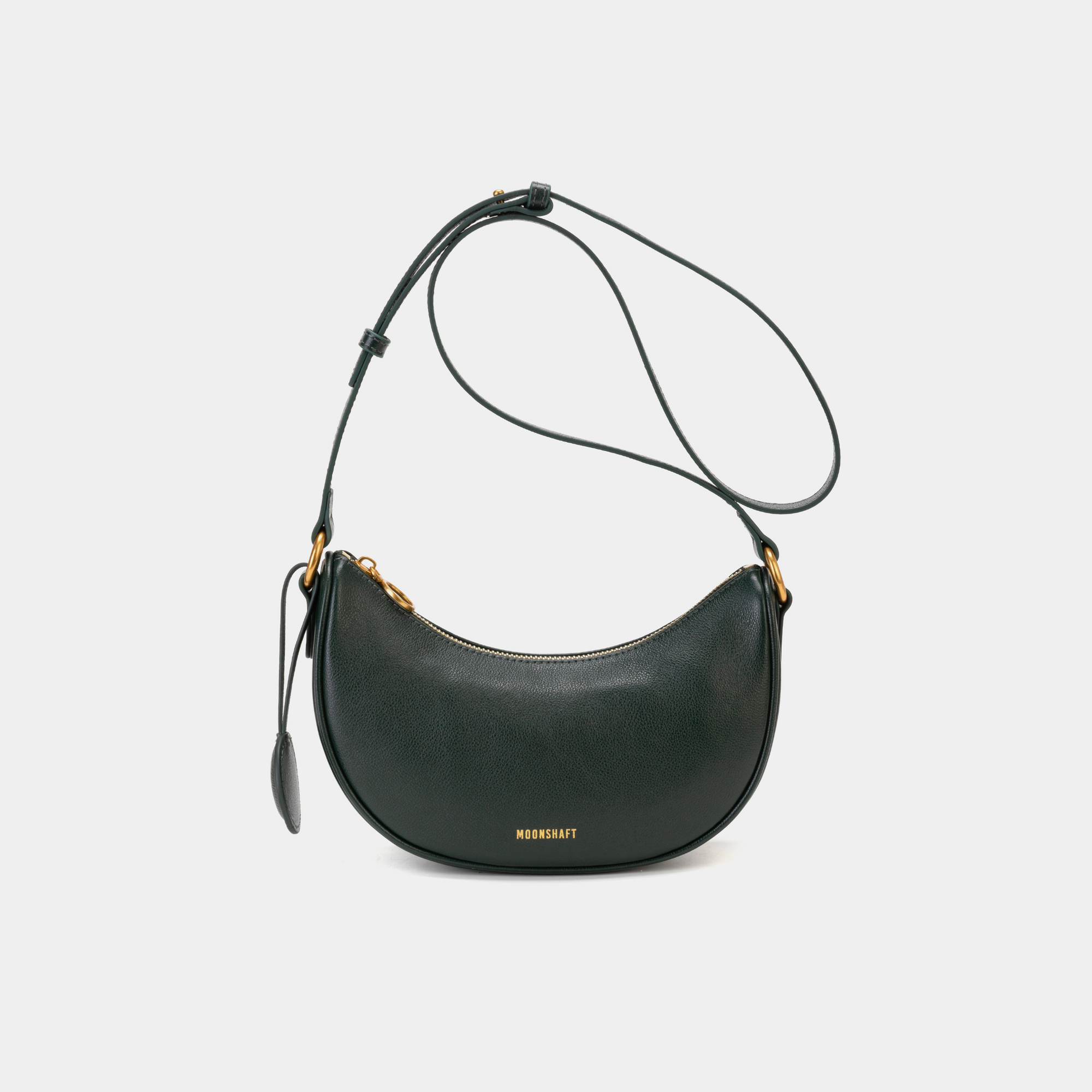Front view of the pine grove Moon bag in caramel, featuring smooth leather with a minimalist design. The bag is shown with its adjustable crossbody strap and gold-tone hardware, highlighting the curved silhouette and simple elegance of the design.