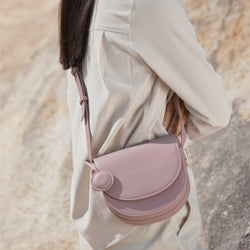 Close-up view of the Light Lilac half moon crossbody bag, worn by a model in a beige outfit, highlighting the adjustable leather strap and the minimalist design against a neutral background.