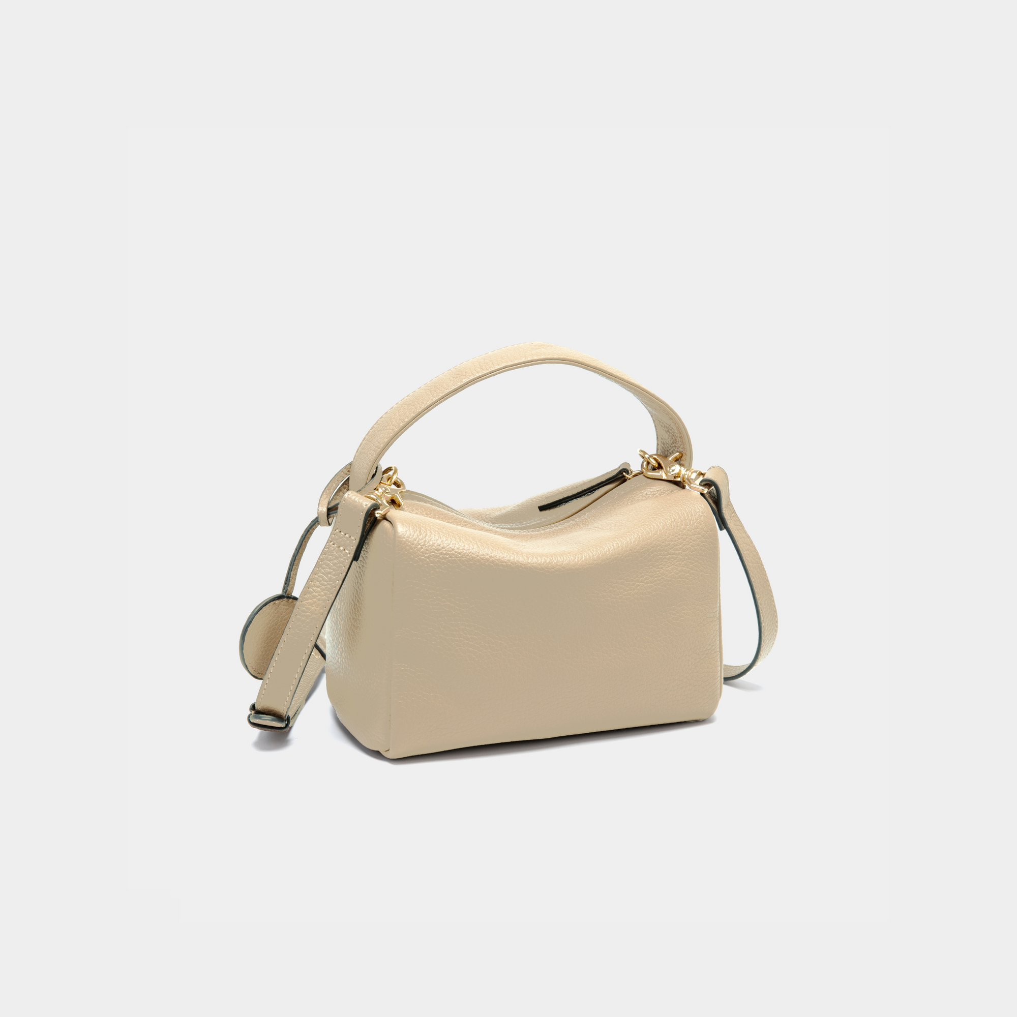 Moonshaft sand-color Loaf Bag from a back-side angle, focusing on the rear of the bag. The bag's structured design and pebbled leather texture are highlighted, with the handle arcing over the top. The detachable shoulder strap drapes to the side, showcasing the bag's versatile carry options. The smooth zip closure is visible at the top of the bag.