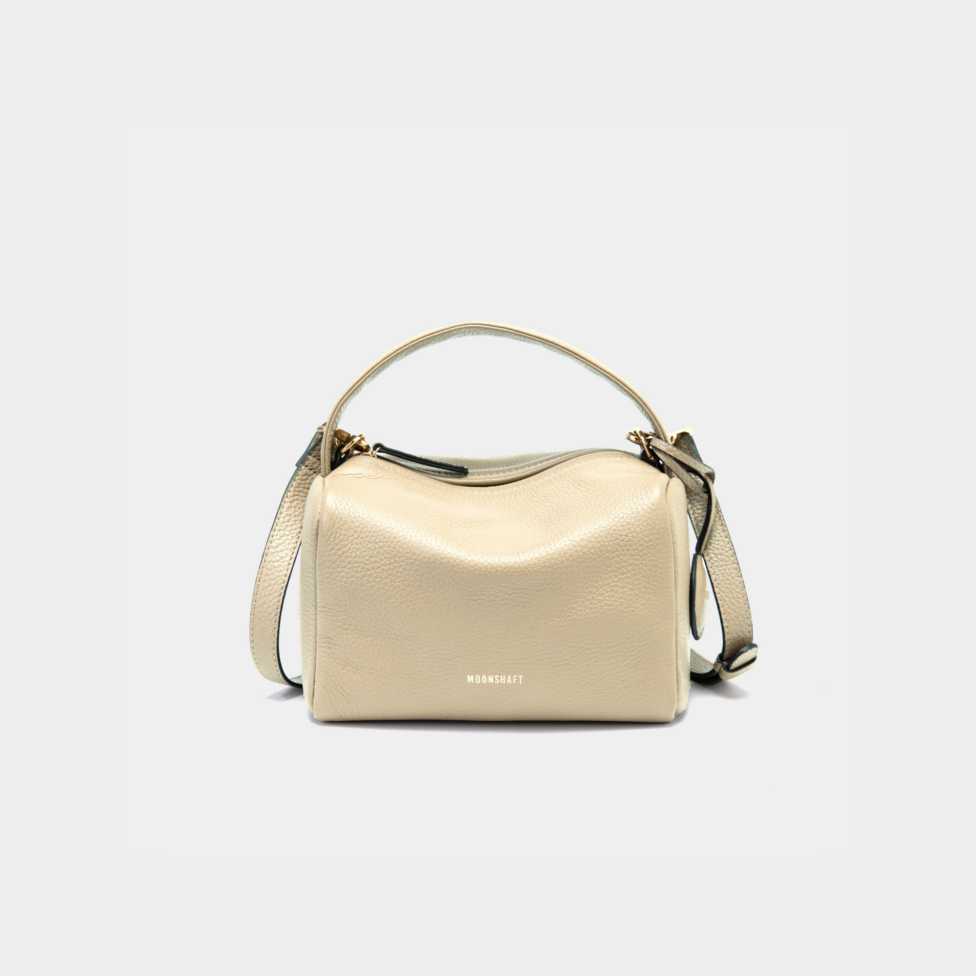 Moonshaft Loaf Bag in sand pebbled leather with a boxy, structured design, featuring a top handle and detachable shoulder strap, along with the Moonshaft logo embossed in gold on the front.