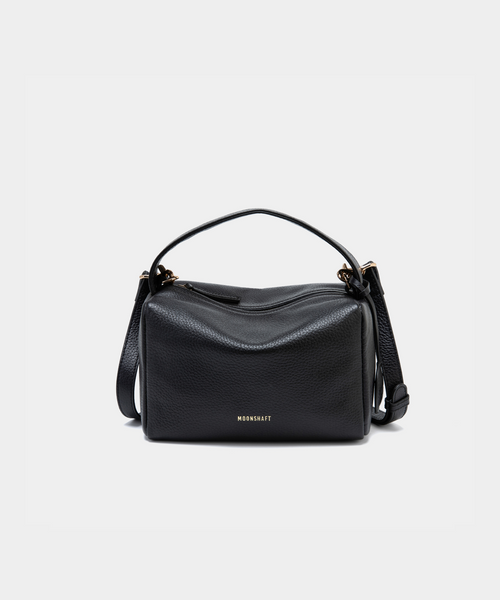 Moonshaft Loaf Bag in black pebbled leather with a boxy, structured design, featuring a top handle and detachable shoulder strap, along with the Moonshaft logo embossed in gold on the front.