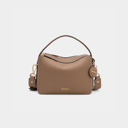 A driftwood-colored upgraded double zip leather bag displayed from a front angle against a plain background. The bag showcases a minimalist design with pebbled leather and two prominent zippered compartments. The structured form and gold-tone zippers add both functionality and a sleek, modern touch. The neutral driftwood color enhances the bag's versatile appeal, making it suitable for a variety of outfits and occasions.