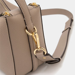 A close-up side view of the upgraded double zip leather bag in sandstone, highlighting the gold-tone hardware and detachable strap. The smooth leather texture and detailed stitching are visible, showcasing the bag’s craftsmanship. The gold-tone clasp engraved with 'MOONSHAFT' connects the strap to the bag, adding a luxurious touch. The neutral sandstone color complements the minimalist design, while the focus on the hardware emphasizes the bag's durability and elegant style.