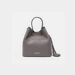 Grey-colored pebbled leather bucket bag with gold accents, featuring a drawstring closure and a compact design. The MOONSHAFT logo is embossed in gold at the bottom front. A small round leather accessory is attached to the side for added detail.