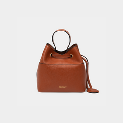 Tan-colored pebbled leather bucket bag with gold accents, featuring a drawstring closure and a compact design. The MOONSHAFT logo is embossed in gold at the bottom front. A small round leather accessory is attached to the side for added detail.