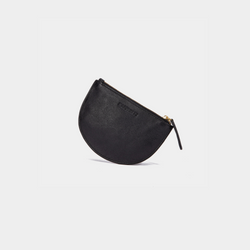 The Half Moon Coin Purse is positioned upright, resting on its curved bottom edge, creating a slight tilt. The zipper is fully closed, and the leather pull tab hangs naturally to the side. The goat leather texture is smooth, with the MOONSHAFT branding subtly embossed near the top center. The product appears balanced, highlighting its slim profile and elegant shape.