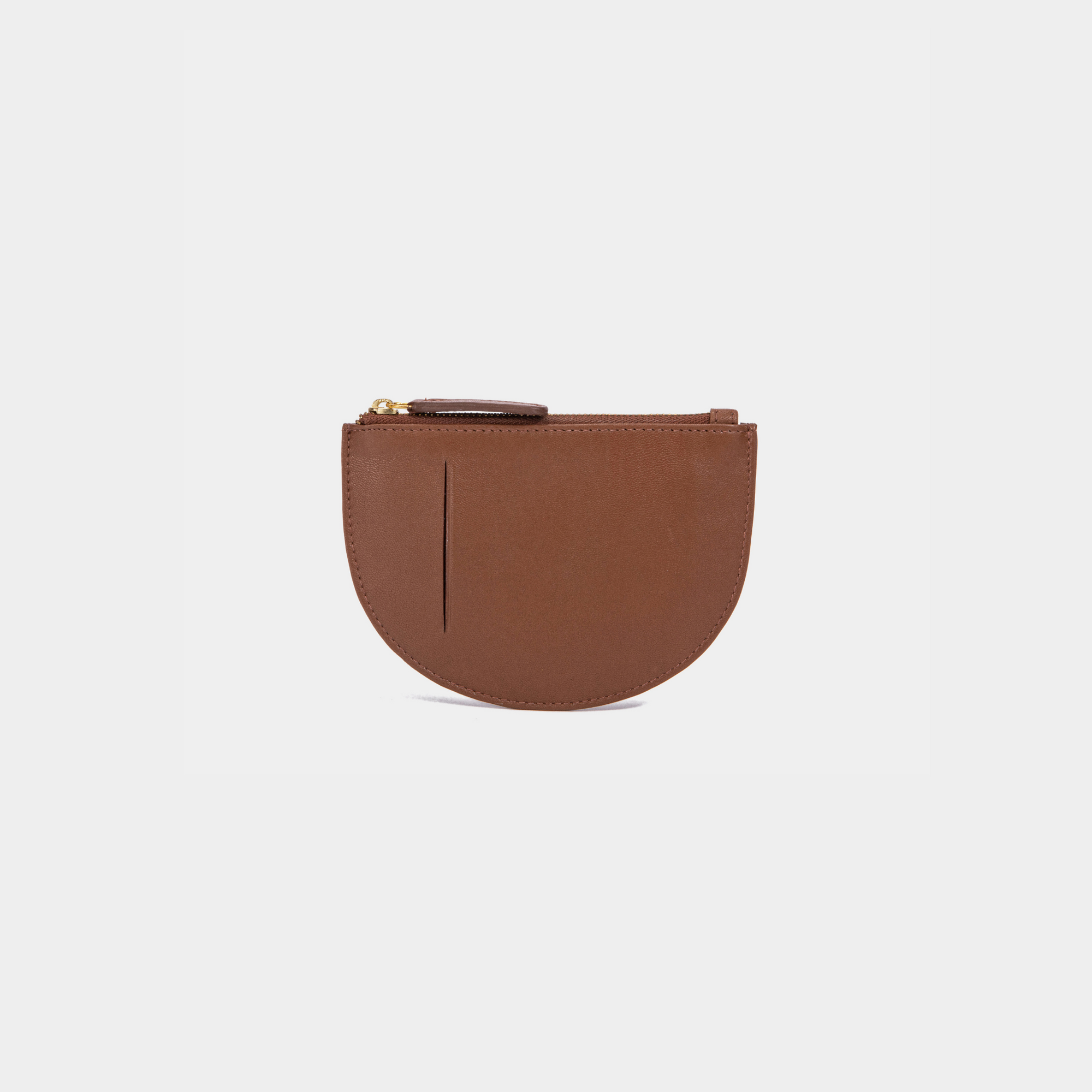 The back view of a cognac Half Moon Coin Purse made of goat leather with a card slot on the back and a top zipper.
