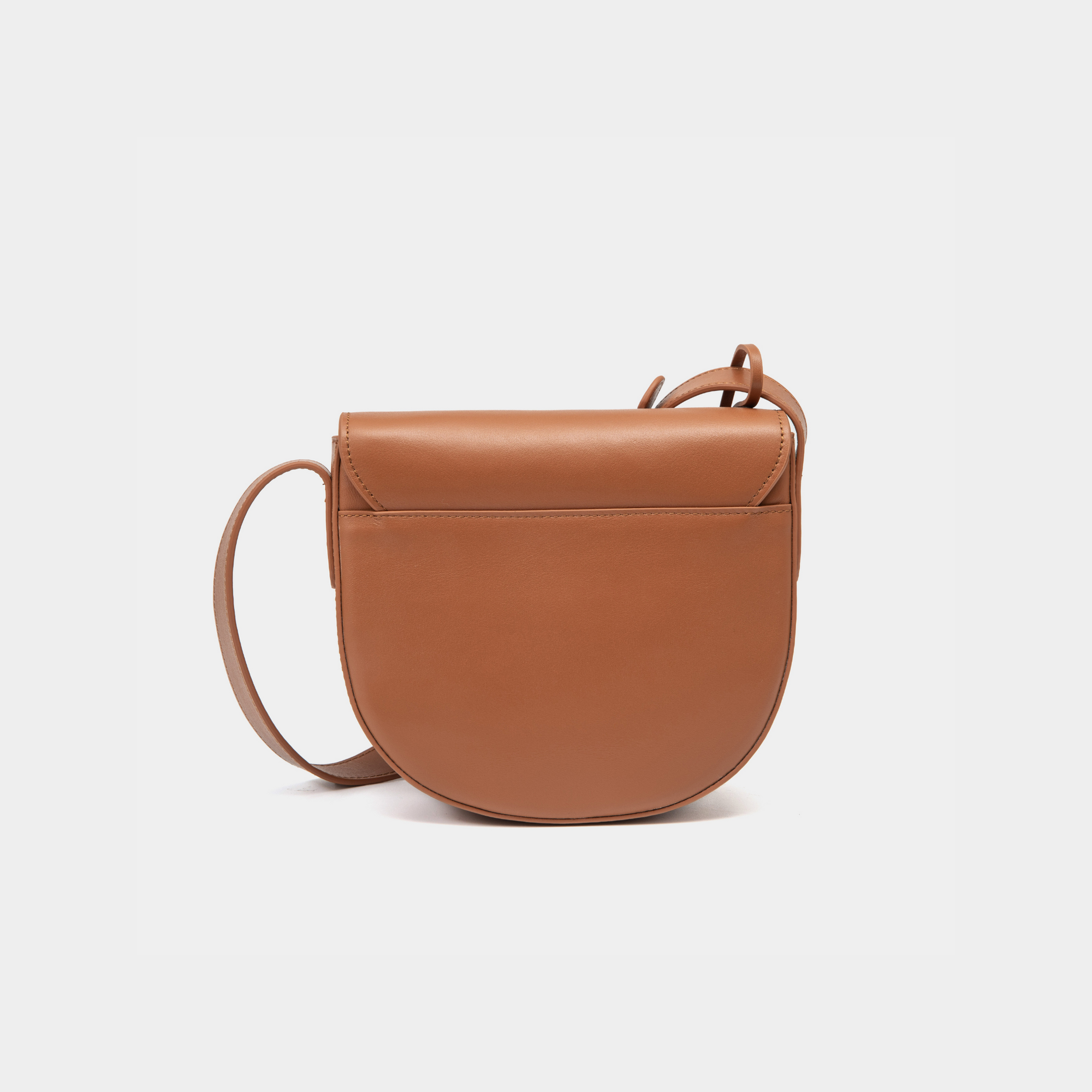 A back view of the half-moon crossbody bag in caramel leather, showcasing its smooth, rounded structure. The back of the bag features clean, minimalist detailing, highlighting the high-quality craftsmanship. The adjustable strap connects seamlessly to the body of the bag, maintaining its sleek, functional design.