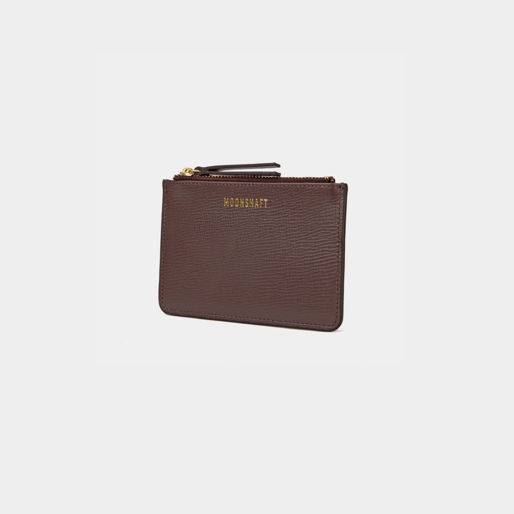 A brown leather cardholder in a standing position, angled slightly to the right. The cardholder has a textured leather surface, with the MOONSHAFT logo embossed in gold at the top. The zipper closure at the top has gold-tone hardware, and there is a small leather zipper pull for ease of use.