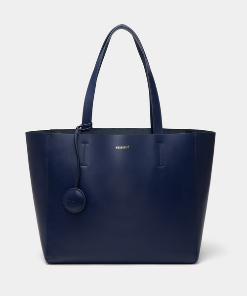 A navy blue leather tote bag displayed from the front, highlighting its minimalist and structured design. The bag features a smooth leather texture with no external pockets or embellishments, emphasizing its sleek and elegant appearance. Two sturdy leather handles are visible, and the black color enhances its versatility, making it a stylish accessory for various outfits and occasions. The clean lines and spacious design offer practicality, making this tote suitable for everyday use.